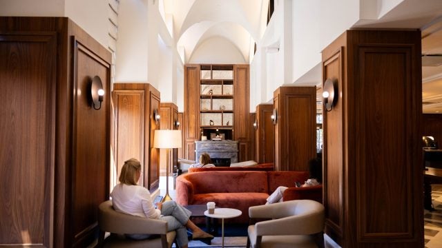 A woman sits reading in a hotel lobby