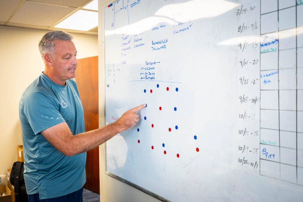 A coach looks over a game plan on a white board