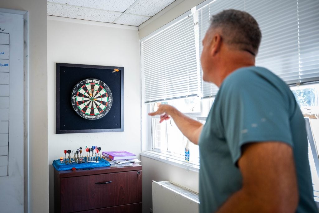 Man in blue shirt throws at a dartboard