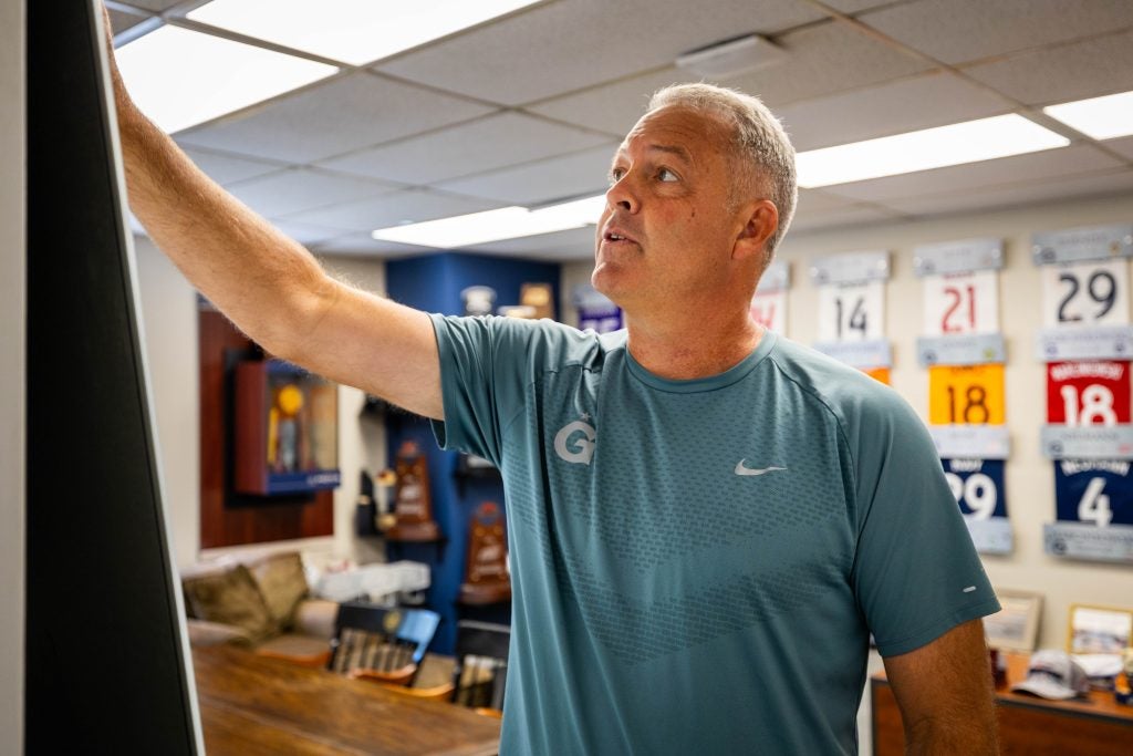 A coach works on a whiteboard in his office