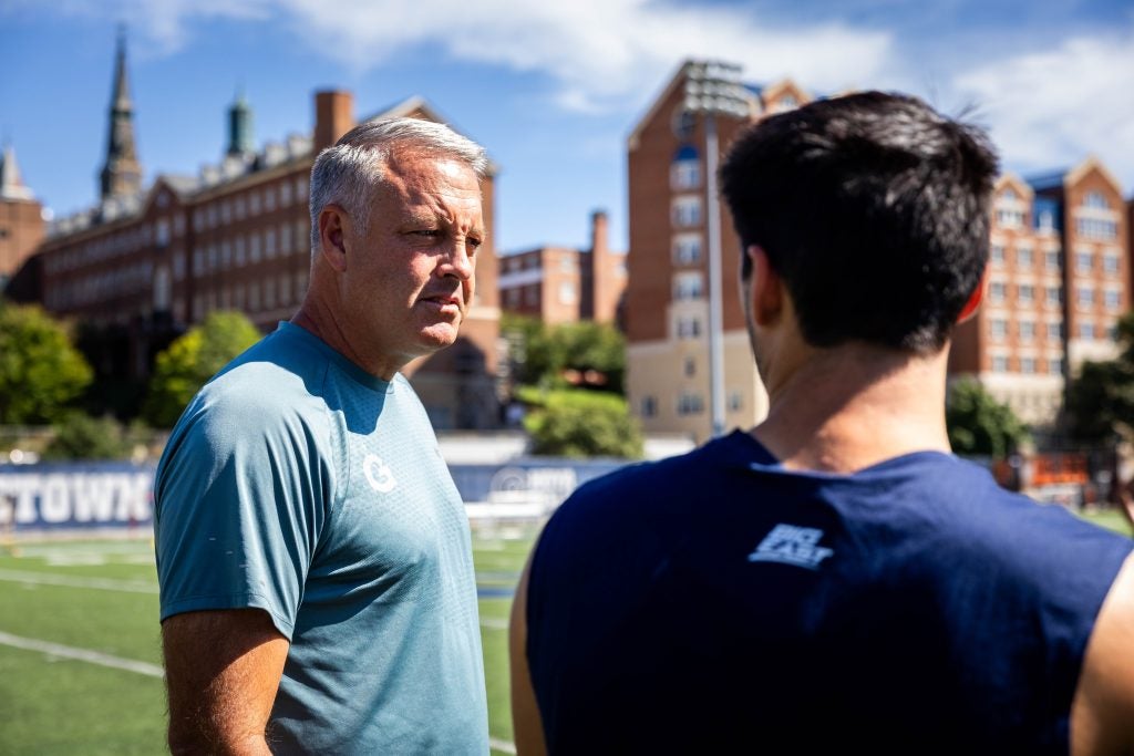 A coach talks to one of his players on a field