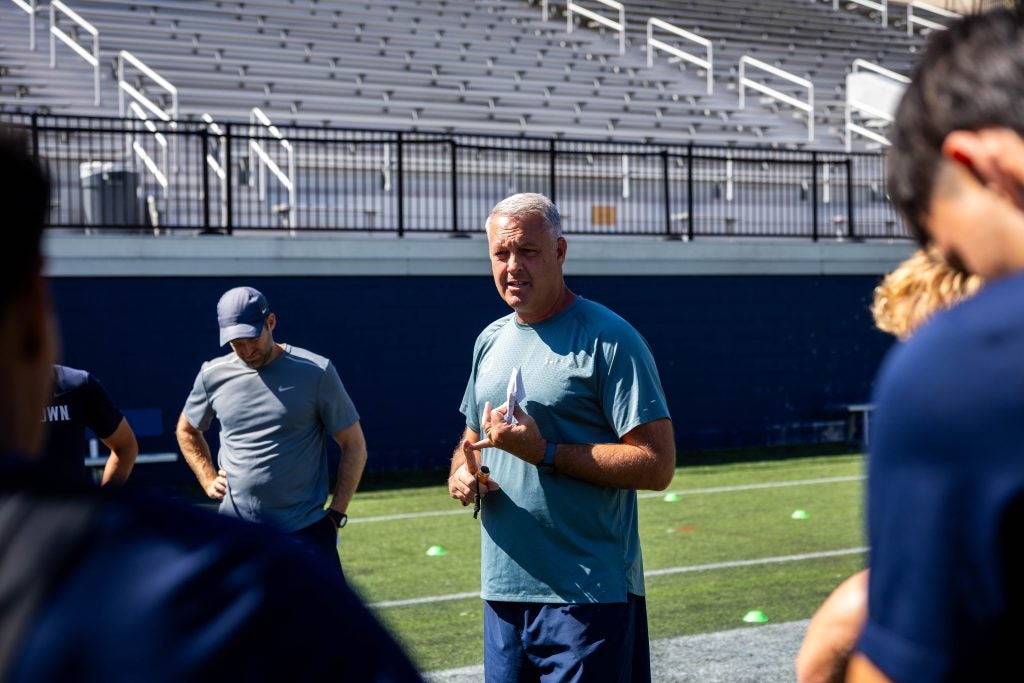 A coach talks to his soccer players on a field
