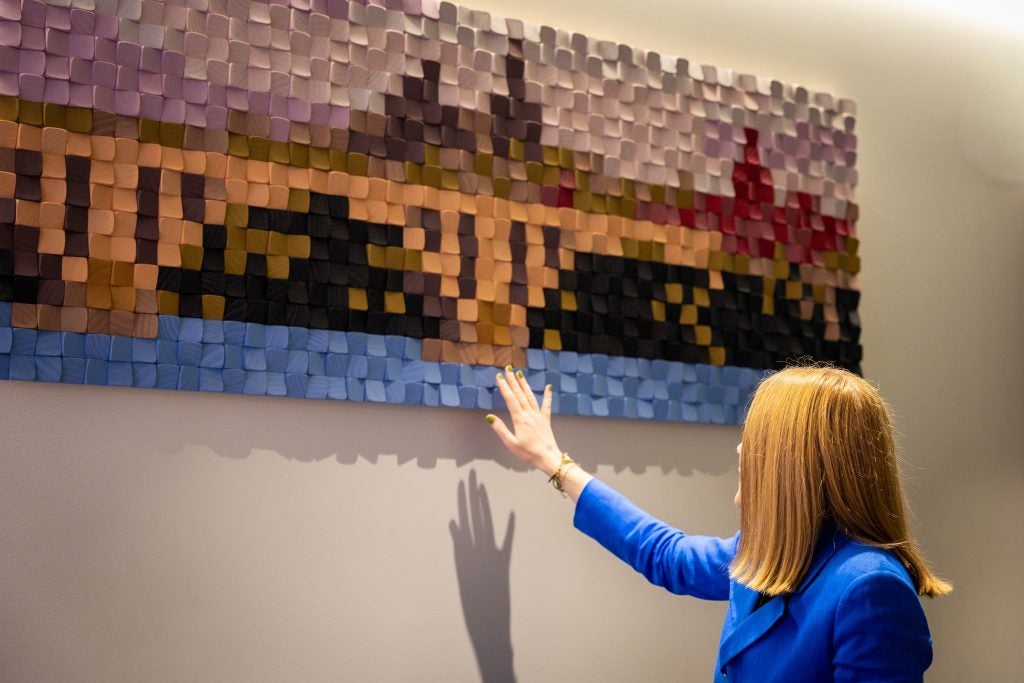 A woman in a mobility scooter touches tactile art in a sensory room