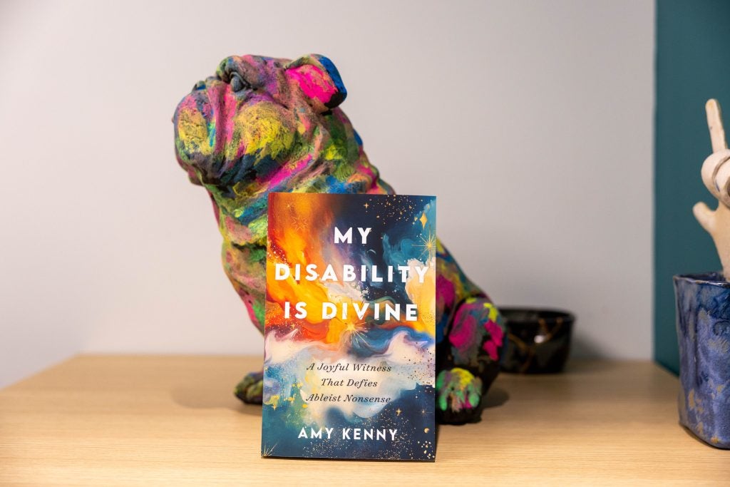 A multicolored toy bulldog and a book that says, "My Disability Is Divine"