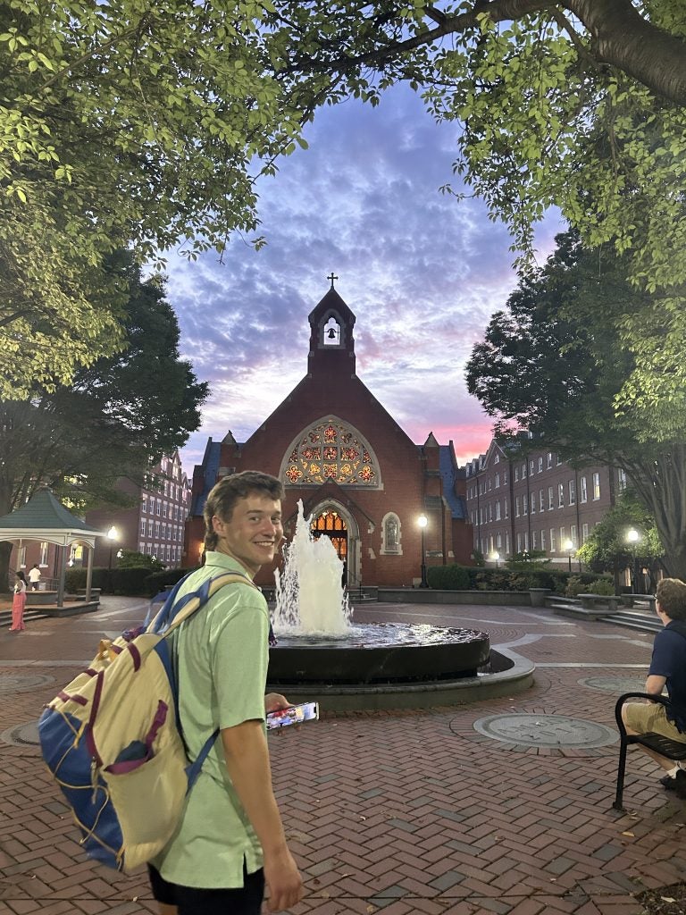 Young man with backpack in the evening by Dahlgren Chapel