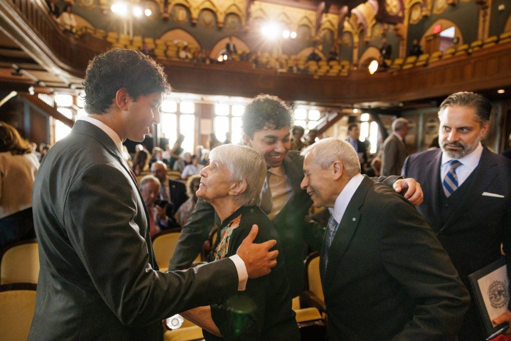 A group of grandsons and grandparents greet and hug one another.