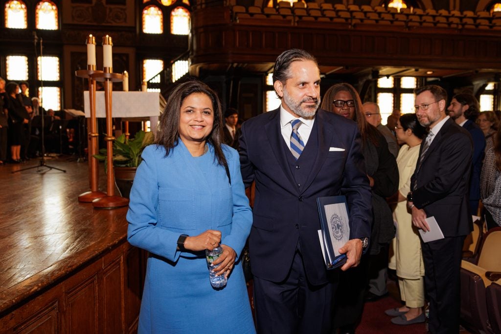 President Peñalver in a black suit and tie stands next to his wife in a bright blue dress