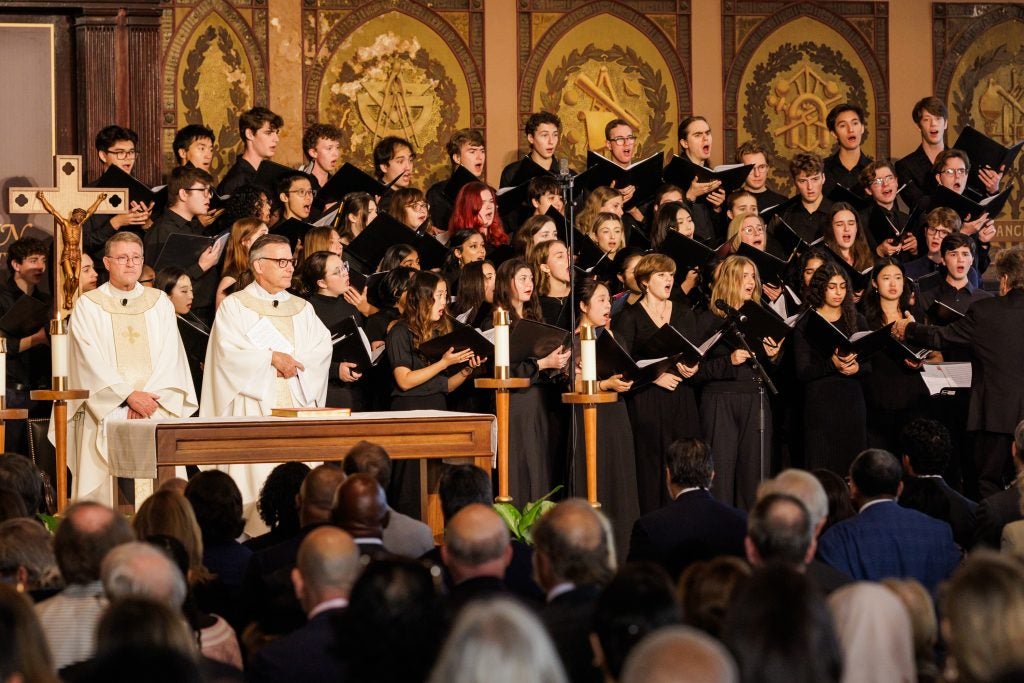 A choir and two priests onstage celebrate a Mass