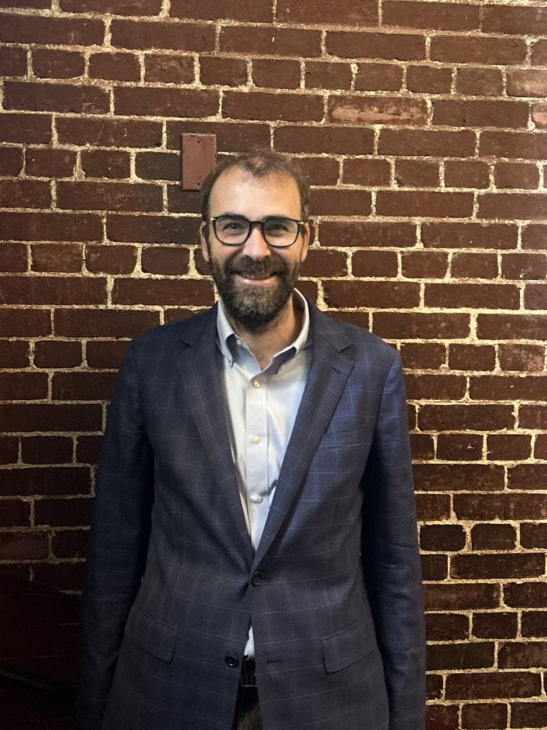 Man in suit with glasses in front of brick wall