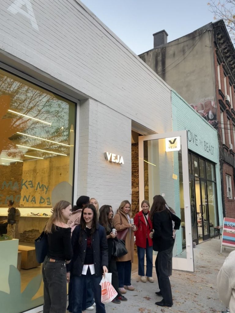 A group of people outside of a VEJA store