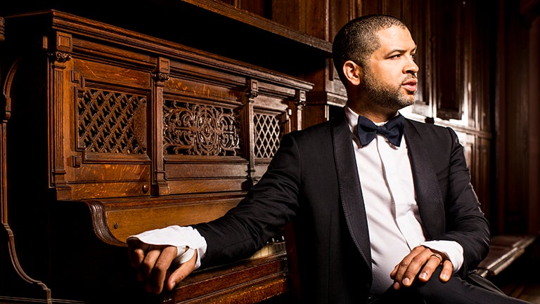 Jason Moran in tuxedo sitting with hand on piano