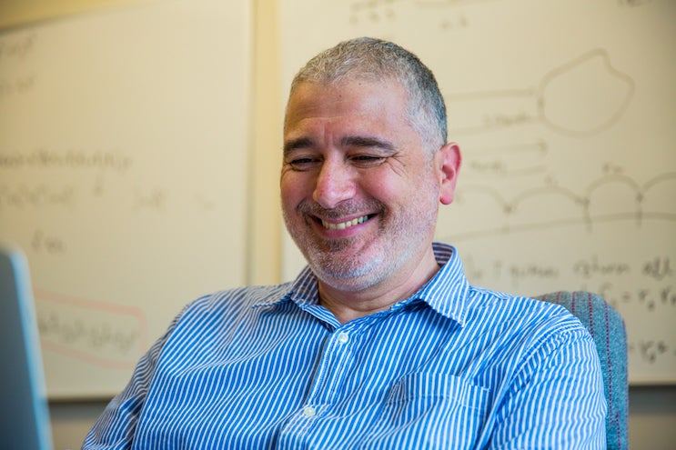 Professor Kobbi Nissim smiles as he looks at a computer in his office.