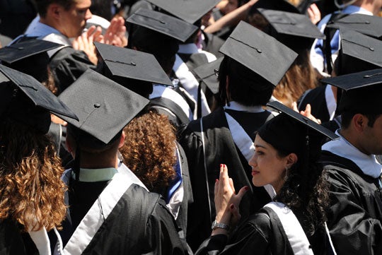 An overhead shot of students, dressed in caps and gowns, seated for commencement. 