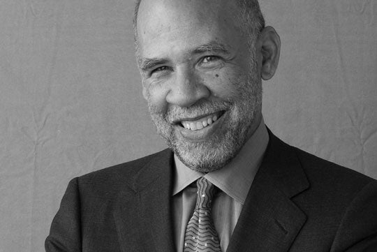 John A. Payton smiles in a black and white headshot.