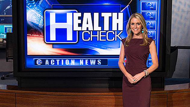 Ali Gorman (NHS’97) in front of a tv screen that says Health Check, 6 Action News.