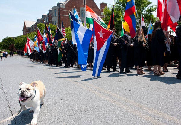 Jack Jr. the bulldog joins the academic procession of students holding their country flags
