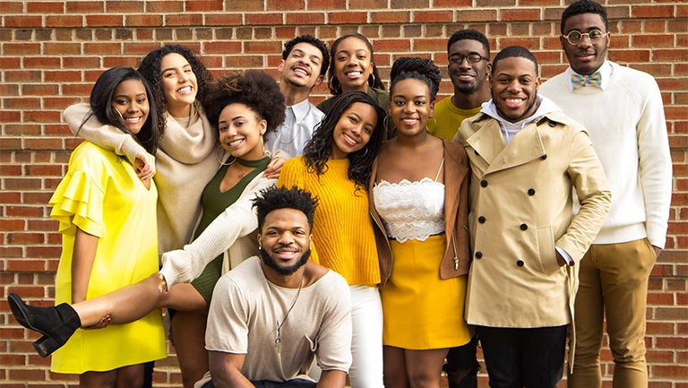 Members of Black Student Alliance leadership pose together dressed in yellows, khakis and greens.