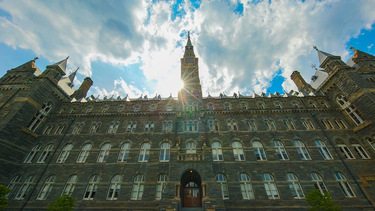 Photo of Healy building on Georgetown campus with sunlight behind its tower