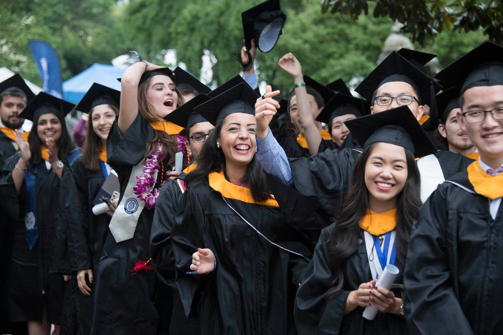 Graduates smile, laugh, and throw their caps in the air at SFS Commencement.