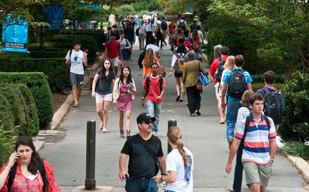 Students walking past signs on Copley Lawn