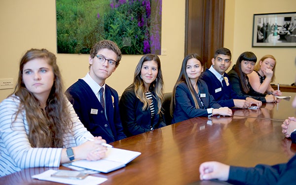 Students look forwatrd as they sit around a table listening to Congressional staffers