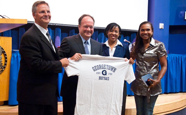 Joe Bozich, John J. DeGioia and apparel workers Maritza Vargas and Elba Nurys Olivo Pichardo hold up a Georgetown shirt.