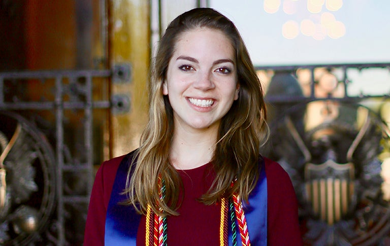 Rachel Azafrani smiles standing outside in front of the entrance to Healy Hall.