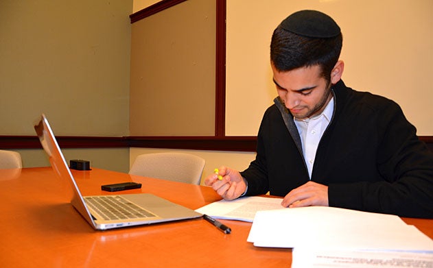 Daniel Bral sits at a table and highlights a paper. 