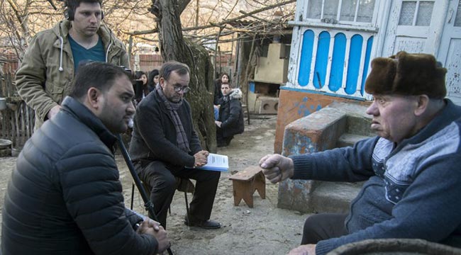 Rev. Patrick Desbois interviews Moldova residents with students surrounding him