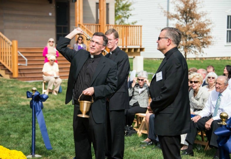 Rev. Kevin O'Brien, S.J., vice president of mission and ministry, blesses the new center as Rev. Patrick Conroy, S.J. look on.
