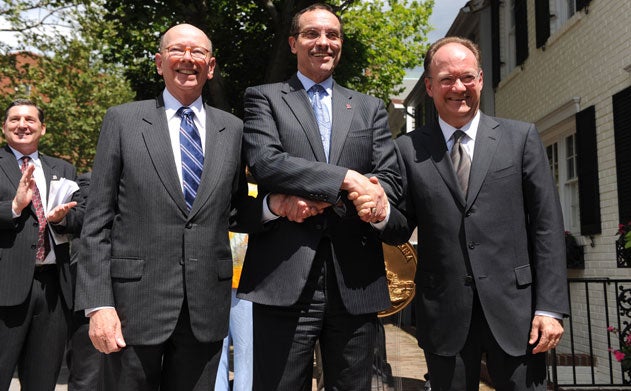 Vincent Gray crosses his arms as he shakes hands with Ron Lewis and John J. DeGioia as another man looks on outside a townhouse