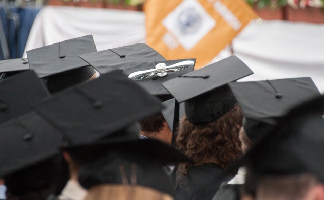 Black graduation caps atop the heads of college graduates at Georgetown University, one has a propellor decoration