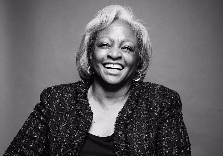 A black and white photo of Carol Anderson smiling while sitting down