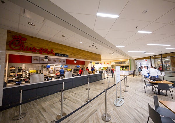 Workers dressed in blue shirts prepare for customers in Chick-fil-A Express eatery