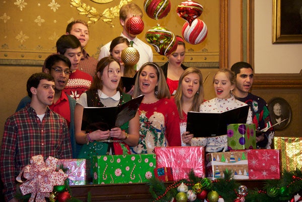 A singing group stands with music folders behind presents while singing