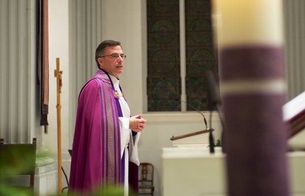 Rev. Kevin O'Brien seen behind a pillar talks to an audience