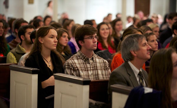 Attendees look on seated in pews