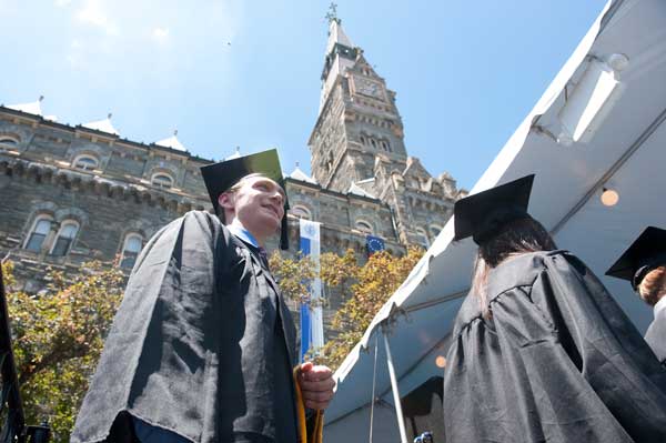 Looking up at a graduate about to walk across the stage with Healy clock tower in the background