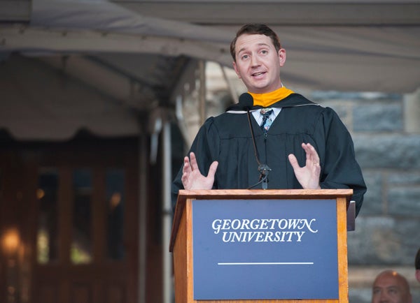 Tim O'Shaughnessy speaking at podium on stage on Healy Lawn