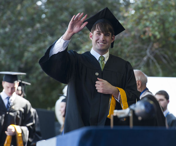 SFS Graduate waves to crowd while walking across stage on Healy Lawn