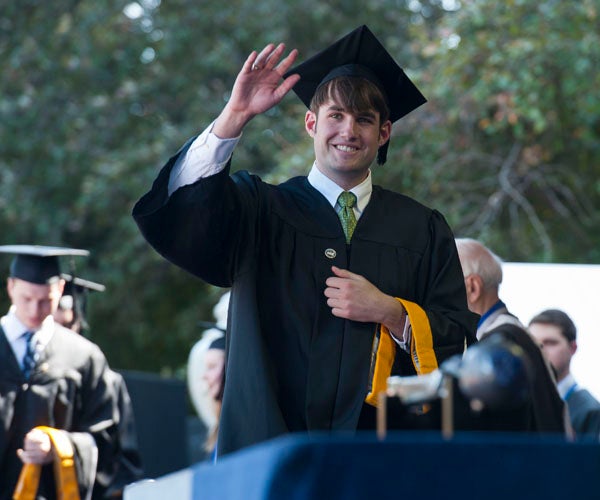 SFS Graduate waves to crowd while walking across stage on Healy Lawn