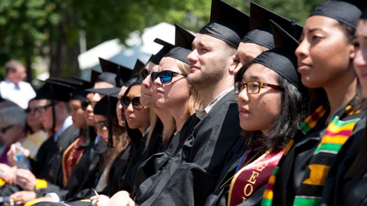 NHS Graduates look on while sitting on Healy Lawn