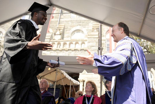 Jeff Green approaches John J. DeGioia while walking across stage