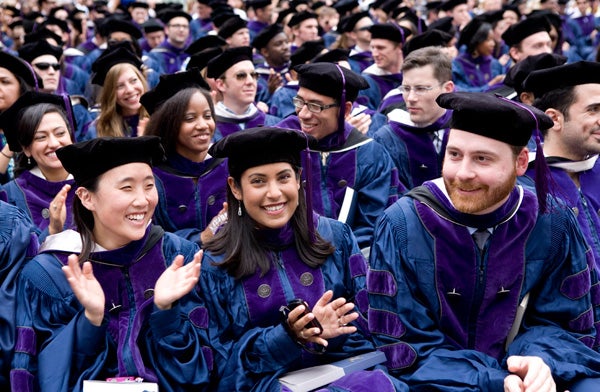 Law Graduates smile while seated on Healy Lawn