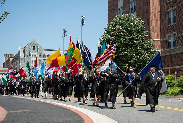 Graduating seniors marching with flags representing their countries 