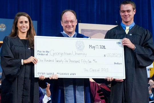 John J. DeGioia holds a large check at 2012 Senior Convocation with Katie Eisenstein (C'12) and Christopher Butterfield (B'12)