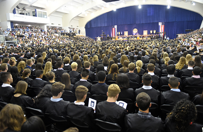 incoming students dressed in their robes are viewed from the back as they listen to New Student Convocation speakers.