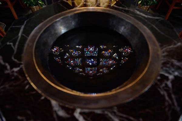 The rose stained-glass window over Dahlgren Chapel’s entrance door reflects off the holy water font.