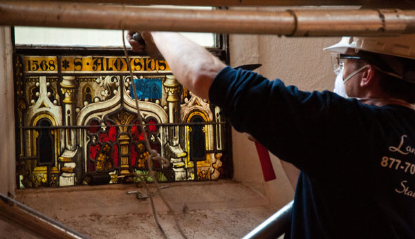 A worker removes a stained glass panel that makes up an image of St. Aloysius of Gonzaga during the Dahlgren Chapel renovation.