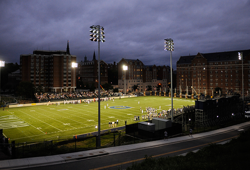 Cooper Field at night with spectators in stands and players on the football field.